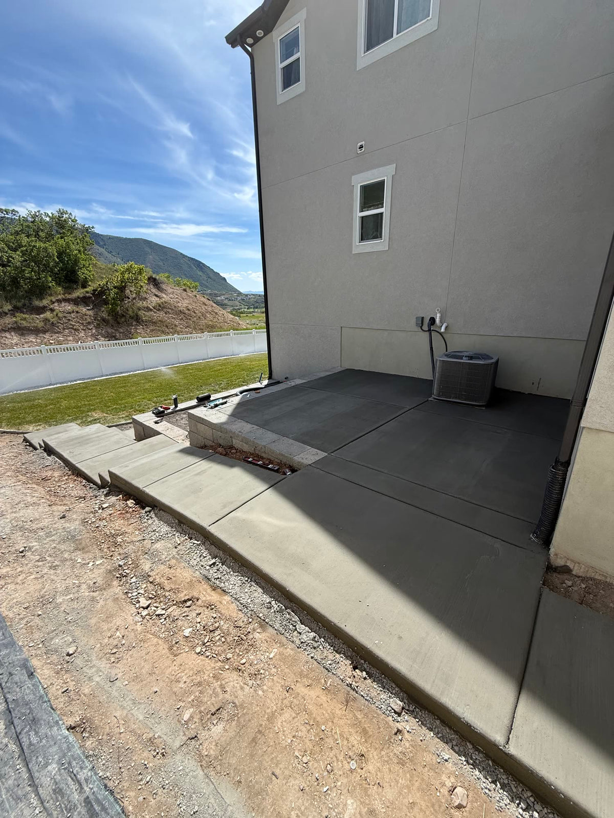 Concrete walkway wrapping around a home to a rear patio in Utah County