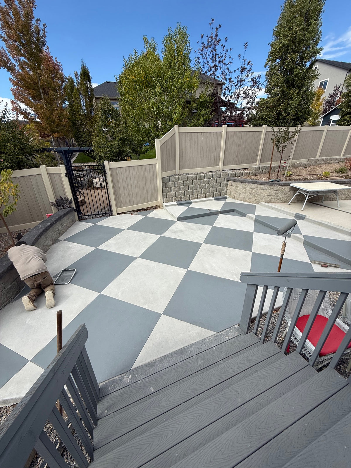 Applying a grey and white checkerboard stain to a decorative concrete patio in Lehi, UT